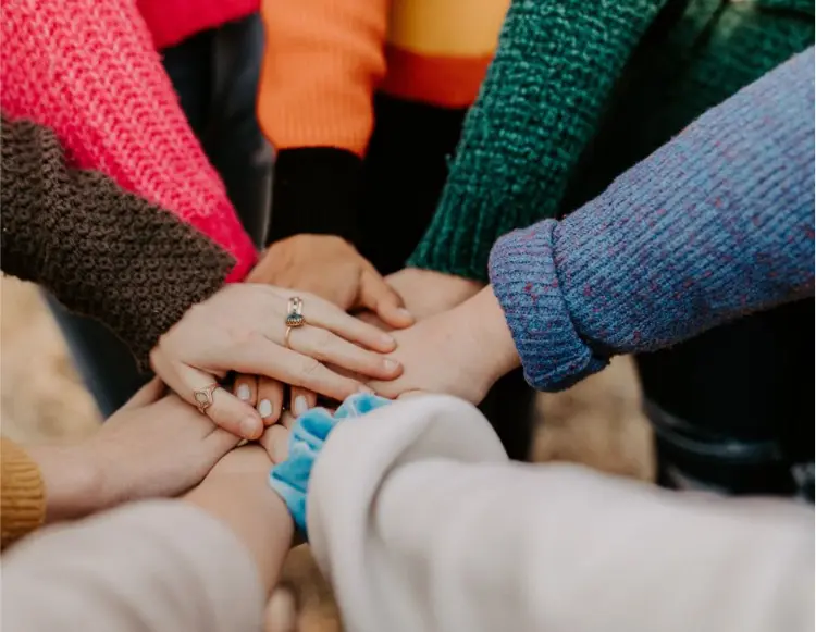 Bli medlem i Teija – gemenskap i fokus Flera händer i ring med färgglada tröjor – symbol för gemenskap och medlemskap i Teija - Textil i Järfälla